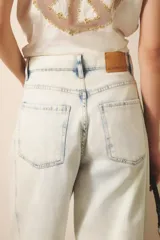 Pantalón jean de tiro medio-alto, calce holgado, relajado, con piernas anchas que se estrechan hacia el tobillo, con largo midi. Confeccionado en denim rígido con lavado bleach, que decolora el tejido hasta dejarlo casi blanco, con reservas de color en costuras y pliegues.