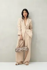 Cartera baguette color marrón claro, confeccionada en símil cuero con formato cilíndrico y doble asa corta.