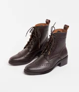 Bota corta de cuero color marrón claro, con cordones y detalles de perforaciones. Tiene un pequeño taco de madera.