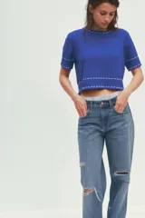 Top azul de tejido de punto con cuello redondo y manga corta. Detalle de pespuntes blancos a contraste en cuello, mangas y ruedo.