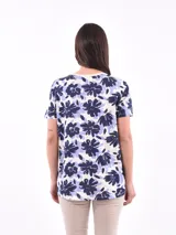 Remera blanca con estampado de flores y hojas en tonos pastel.