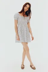 Vestido corto de popelina de algodón con estampado floral azul. Presenta escote cuadrado con elástico, mangas cortas abullonadas con fruncido elástico, cuerpo ajustado fruncido y falda con vuelo.
