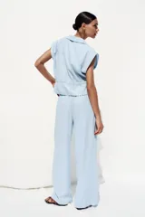 Pantalón celeste de tiro alto con cintura elástica, bolsillos delanteros y pernera ancha.