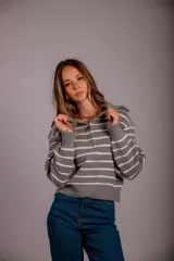 Sweater de punto color beige con rayas horizontales blancas, cuello polo con cierre de cremallera y mangas largas.