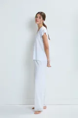 Conjunto de pijama blanco de algodón, compuesto por una remera de mangas cortas con cuello en V y detalle de calado en los bordes, y un pantalón largo de corte recto con calado en el ruedo.