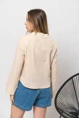 Camisa color beige simil lino, de corte recto y mangas largas con puños abotonados.