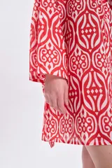 Vestido camisero corto de algodón con estampado geométrico en tonos rojo y blanco, cuello camisero, mangas largas y corte recto.