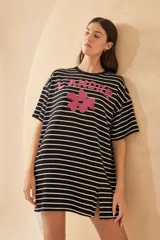 Vestido corto tipo remerón a rayas horizontales blancas y negras, con estampa frontal de una flor y la palabra 'L'AMOUR' en color fucsia. Tiene mangas cortas y aberturas laterales en el ruedo.