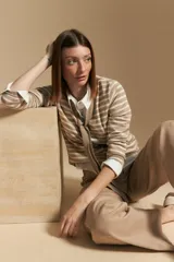 Cárdigan de tejido de punto a rayas horizontales anchas, color crema y negro. Presenta un cuello tipo chal que se anuda al frente como un lazo.