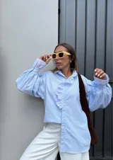 Camisa celeste a rayas verticales con cuello clásico y volados con bordado inglés en el frente y los puños.