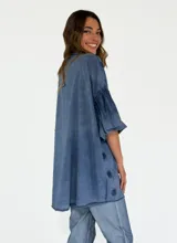 Camisa color lila con textura de lunares en relieve, de corte holgado, manga 3/4 con volados y cierre frontal con botones.