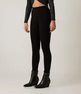 Pantalón negro de corte skinny confeccionado en tejido de punto roma. Diseño de sastrería con costuras frontales y cierre lateral con cremallera.