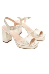 Sandalias doradas con plataforma y taco alto, tiras finas y hebilla lateral.