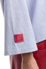 Remera blanca de manga larga con cuello redondo y pequeño logo estampado en el pecho y en la manga.