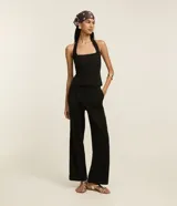 Pantalón wide leg negro de crepé, con cintura alta, pliegues, botón y trabillas.