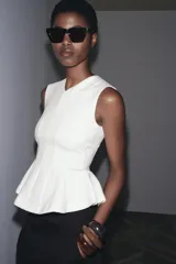 Top blanco de tejido de punto elástico, con cuello redondo, sin mangas y peplum en el bajo.