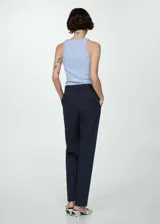 Pantalón de vestir azul marino, de corte recto, con bolsillos laterales y traseros. Se ajusta a la cintura con cinturón de cuero marrón.
