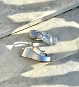 Sandalias doradas con plataforma, tiras cruzadas y hebilla al tobillo.