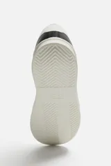 Zapatillas deportivas negras con detalle en blanco en la parte posterior y suela blanca con volumen de diseño irregular.