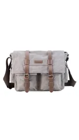 Morral de tela canvas color gris con detalles en cuero marrón. Tiene tapa con hebillas, doble bolsillo frontal, trasero y laterales. Interior espacioso con compartimento para notebook de 15". Correa de galón regulable.
