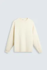 Sweater color crema de tejido de punto suave, con cuello redondo, corte recto y mangas largas con puños acanalados.