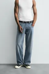 Pantalón de jean gris oscuro, corte amplio, con cinco bolsillos, efecto lavado y cierre frontal con cremallera y botón.