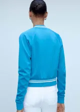 Chaqueta deportiva azul con cierre frontal, cuello redondo y terminaciones con rayas blancas en cuello, puños y ruedo.