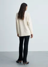 Sweater color beige de tejido de punto con cuello en V y corte oversize.