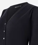 Cardigan blanco de punto, con escote en V, manga larga con detalle de botones perlados en los puños y cierre frontal de botones perlados. Presenta un canesú liso y un borde inferior acanalado.