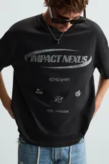 Camiseta negra de corte relaxed fit, cuello redondo y manga corta. Estampado frontal con la frase "Impact Nexus" y otros logos pequeños.