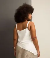 Blusa de satén color blanco, con escote drapeado y breteles finos ajustables. El bajo es irregular.