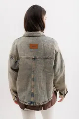 Campera de jean celeste con efecto lavado, corte recto, cuello clásico, cierre frontal con botones metálicos, bolsillos de parche en el pecho y mangas largas con puños abotonados.