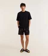 Bermuda de baño masculina confeccionada en microfibra negra con estampado de ballenas blancas. Posee cintura elástica con cordón ajustable y un bolsillo trasero.