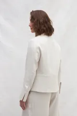 Chaqueta color crema de lino, de corte recto, con cuello camisero y cierre frontal con botones.