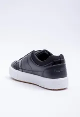 Zapatilla negra con detalles blancos y suela gruesa, diseñada para ofrecer comodidad y estilo.