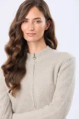 Campera tejida de abrigo color beige, con cierre frontal, cuello alto y bolsillos laterales.