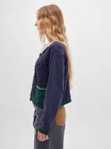 Cardigan combinado con bordados y dos bolsillos delanteros, corte tipo crop y cuello caído con terminaciones tipo corderito.
