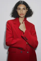 Abrigo rojo de lana con doble botonadura, cuello con solapa y bolsillos con solapa en la parte delantera.