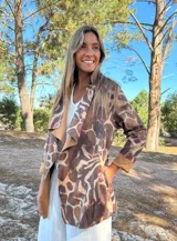 Parka o chaqueta ligera de mujer con cuello solapa y manga larga. Presenta un estampado animal print que combina tonos marrones, beige y detalles en celeste/turquesa.