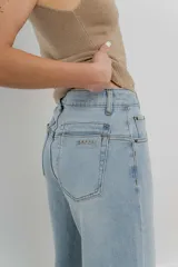 Pantalón de jean celeste claro, corte palazzo, tiro alto, bolsillos delanteros y traseros, y detalle metálico con el logo Peach en el bolsillo trasero.