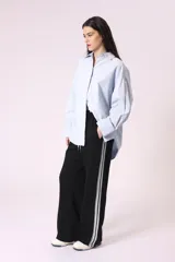 Pantalón negro de corte ancho con cintura elastizada y cordón ajustable. Presenta una franja blanca vertical a lo largo de la pierna.