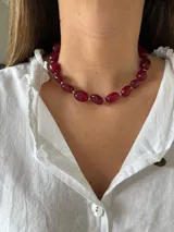Collar tipo gargantilla compuesto por cuentas ovaladas de color rojo oscuro (rubí/granate) separadas por pequeñas cuentas plateadas.