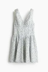 Vestido corto de algodón con estampado floral en tonos azules y amarillos. Tiene escote en pico, breteles anchos fruncidos y cuerpo entallado con costura fruncida en la cintura y falda con vuelo.