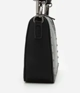 Bolso baguette negro de cuero sintético con asa larga, cierre de cremallera y apliques de spikes y detalles metálicos.