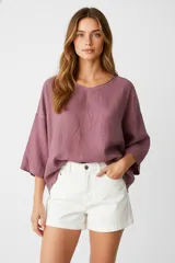 Blusa blanca de algodón con broderie, corte holgado, cuello en V y mangas 3/4 con botón para sujetar.