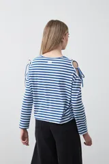 Remera de manga larga a rayas horizontales blancas y negras, con escote redondo y aberturas en los hombros sujetas con lazos regulables de tela a rayas.