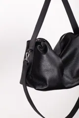 Bolso negro de cuero con doble correa, una corta para llevar al hombro y otra larga regulable y desmontable para usar cruzada. Tiene cierre metálico, bolsillo interior con cierre y bolsillo para celular.