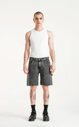 Bermuda de denim gris con efecto desgastado, corte oversize estilo carpintero y múltiples bolsillos.