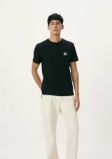 Camiseta blanca de algodón con cuello redondo y mangas cortas. Estampa rectangular con borde negro que contiene la frase "NATURAL ATMOSPHERE" en letras mayúsculas y una imagen de montañas y mar.