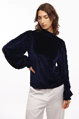 Polera azul marino de terciopelo con cuello alto y mangas largas abullonadas.